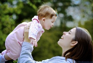 Mother holding up toddler with her arms. 