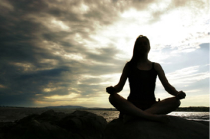 woman sitting meditating outside on a cloudy day.