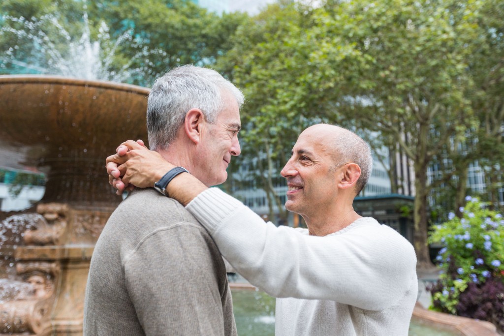 A gay couple looking at each other smiling.