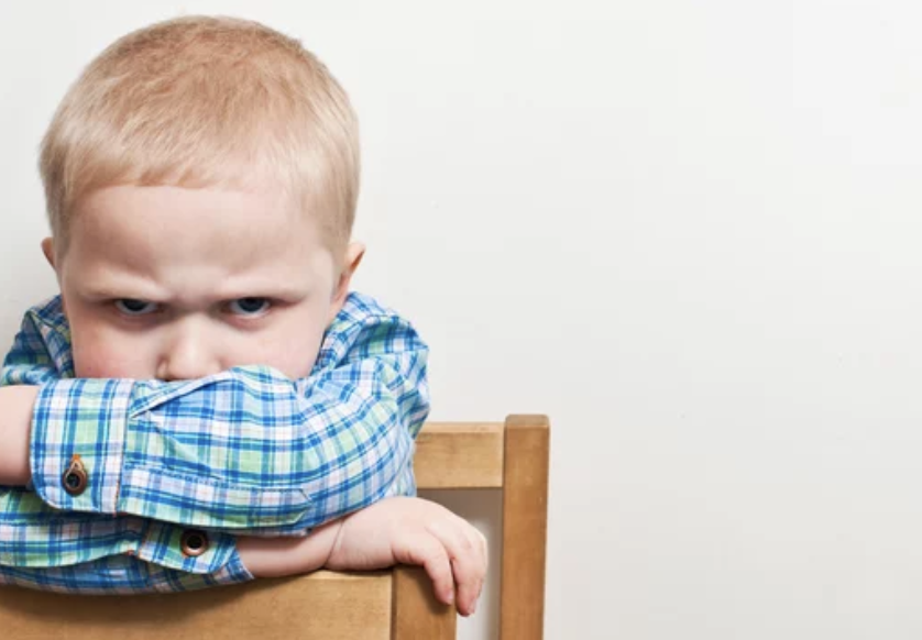 Angry child sitting on chair.