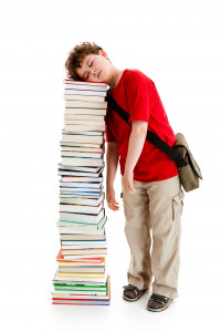 kid falling asleep on tower of school books.