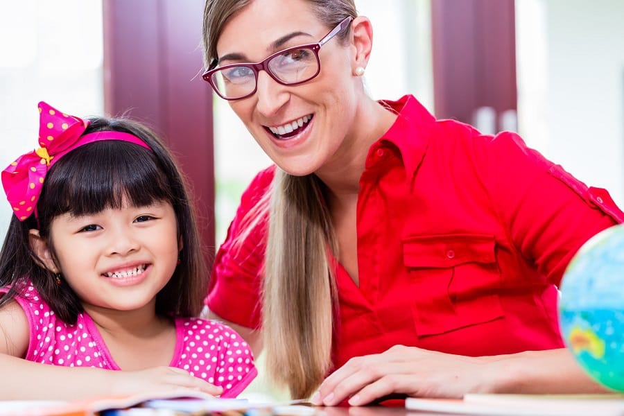 Psychologist and child smiling while reading looking up at camera.