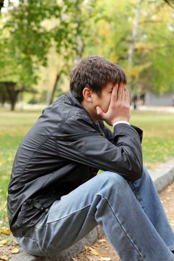 young man covering his face dealing with Chronic pain.