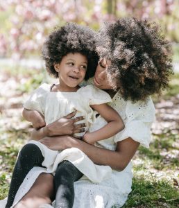 daughter sitting on mothers lap smiling.