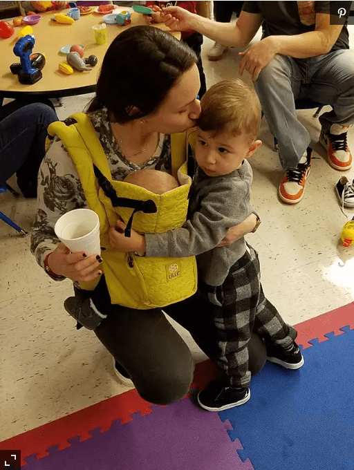 Francyne Zeltser a mother and psychologist kissing her child on forehead in classroom. 