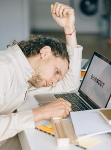 Burnt-out Adult with head down staring at laptop. 