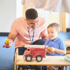 ABA Therapist playing with child in group session.