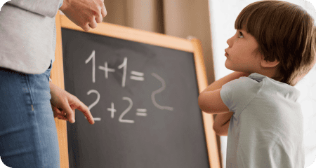 A side view of a child at home being taught mathematics on chalkboard.