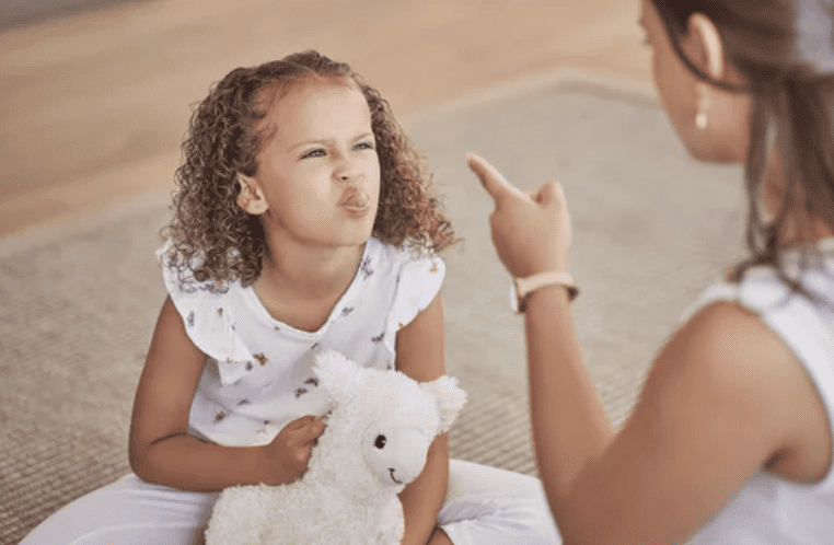 Young girl sticking tongue out not listening to mother.