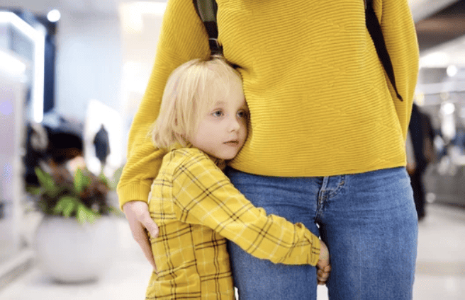 Child with anxiety holding onto mother.