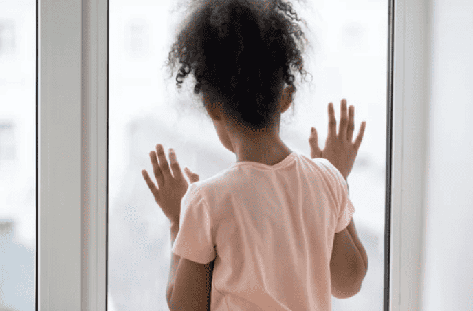 Littler girl with social Anxiety looking out a window