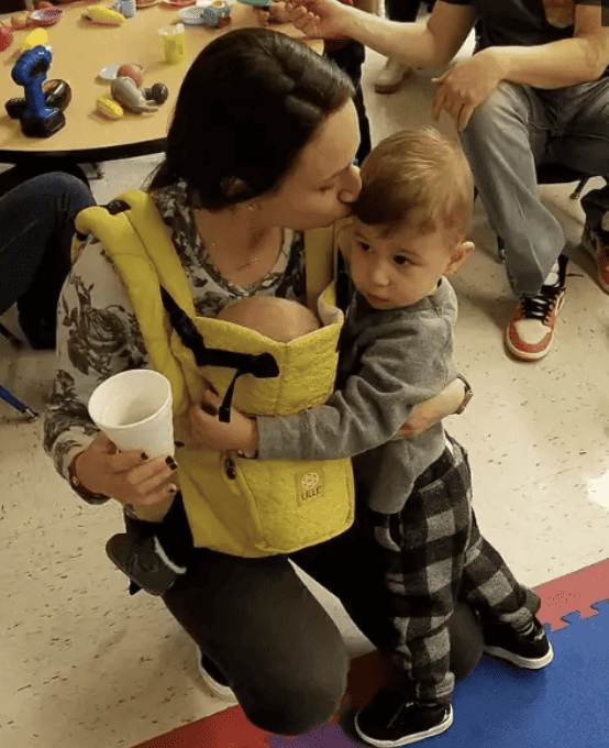 Francyne Zeltser a mother and psychologist kissing her child on forehead in classroom.