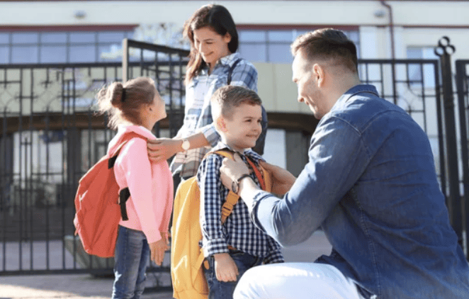 Mother and father saying goodbye to kids on the first day of school