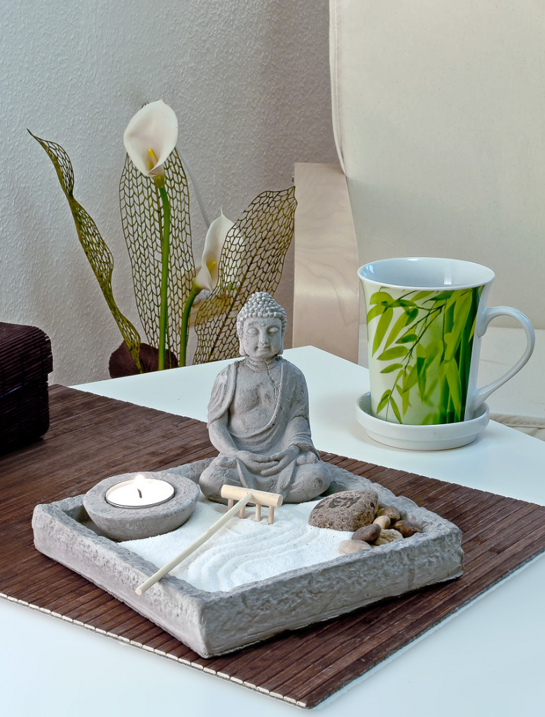 relaxing small buddha statue with sand on table