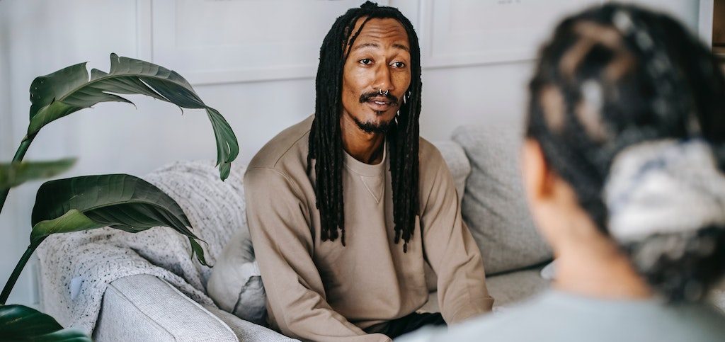 Man sitting on couch in therapy session speaking to psychologist.