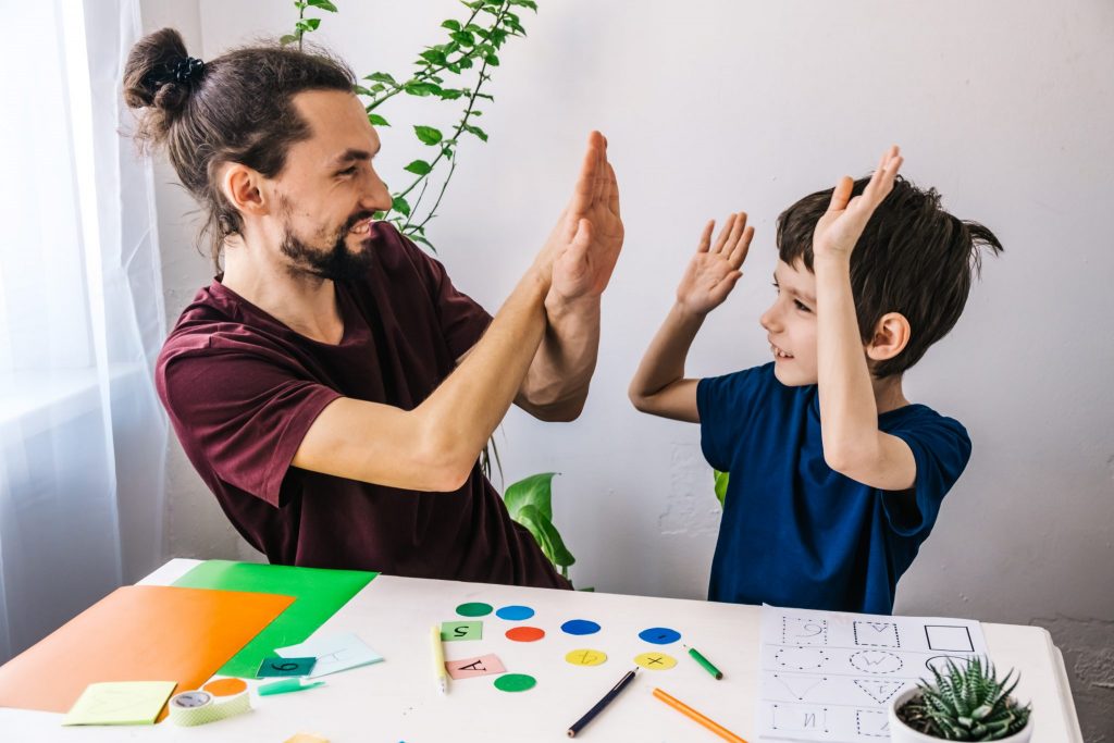 tutor supporting kid with homework in session with high fives.