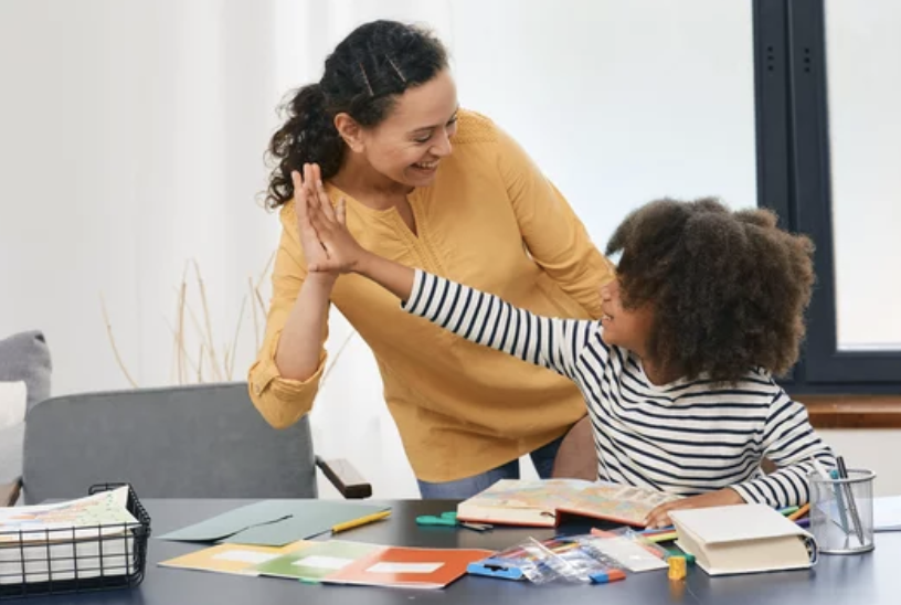 behavior technician giving a young girl a high five for completing a task.