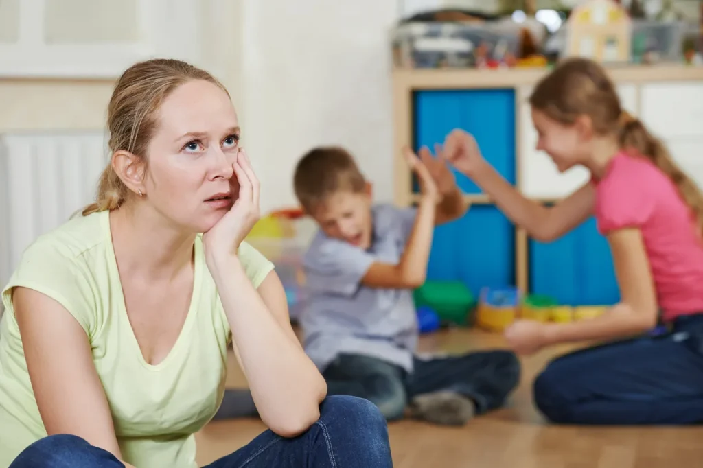 Mom having tough time managing her kids behavior while they argue in the background.